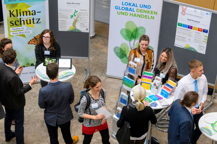 Menschen an Stehtischen vor Plakaten und Aufstellern