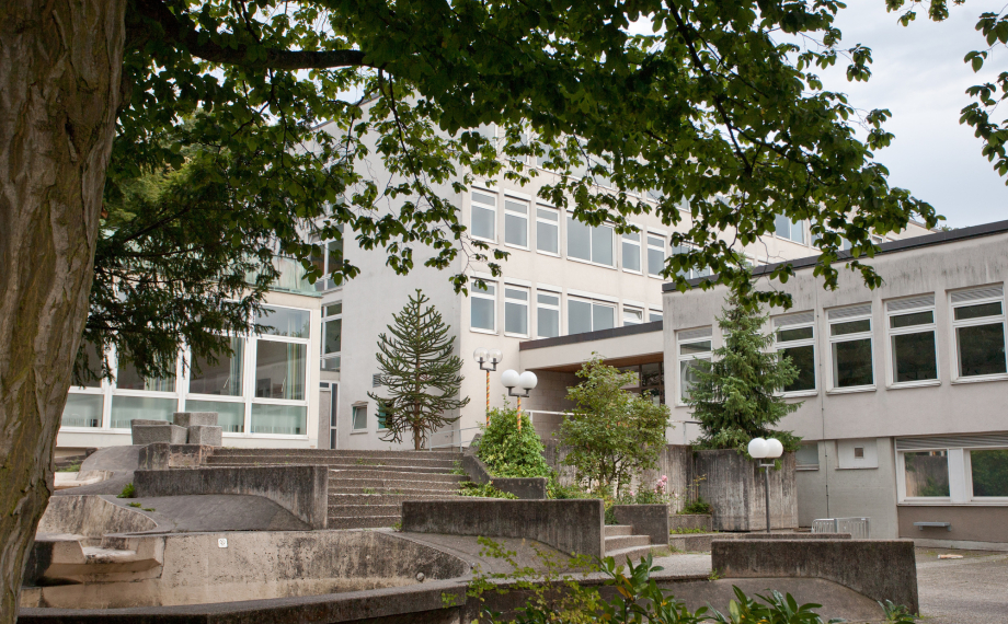 Das Bild zeigt das Kronberg Gymnasium in Aschaffenburg von außen und den Schulhof.