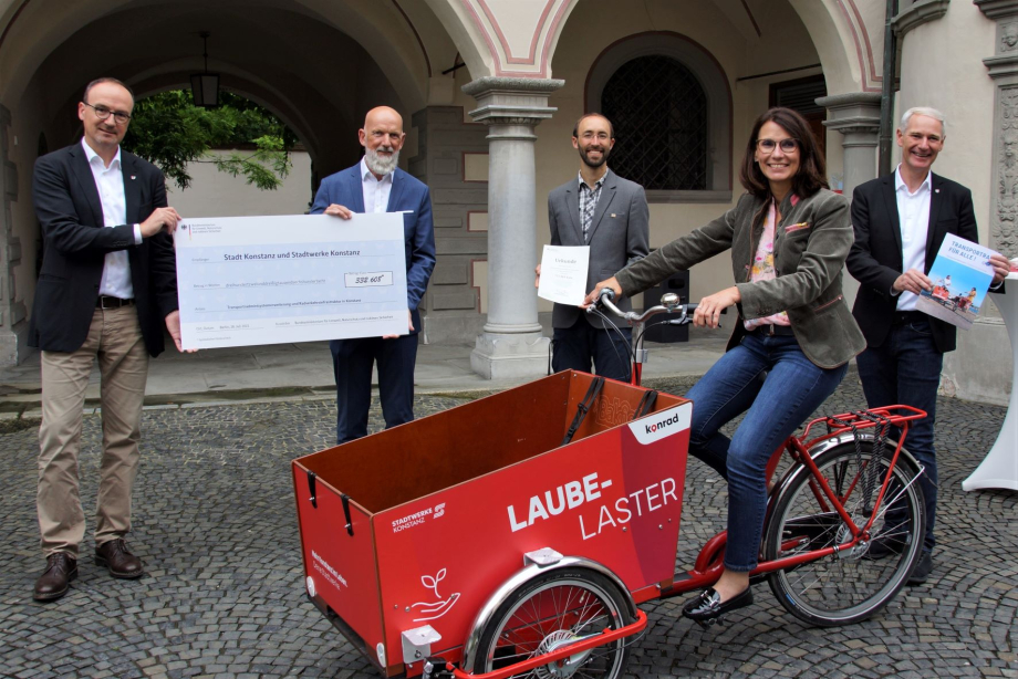 Das Bild zeigt Oberbürgermeister Uli Burchard, Stadtwerke-Geschäftsführer Dr. Norbert Reuter, Radverkehr-Beauftragter Gregor Gaffga, die Parlamentarische Staatssekretärin Schwarzelühr-Sutter auf einem Lastenfahrrad und Bürgermeister Karl Langesteiner-Schö