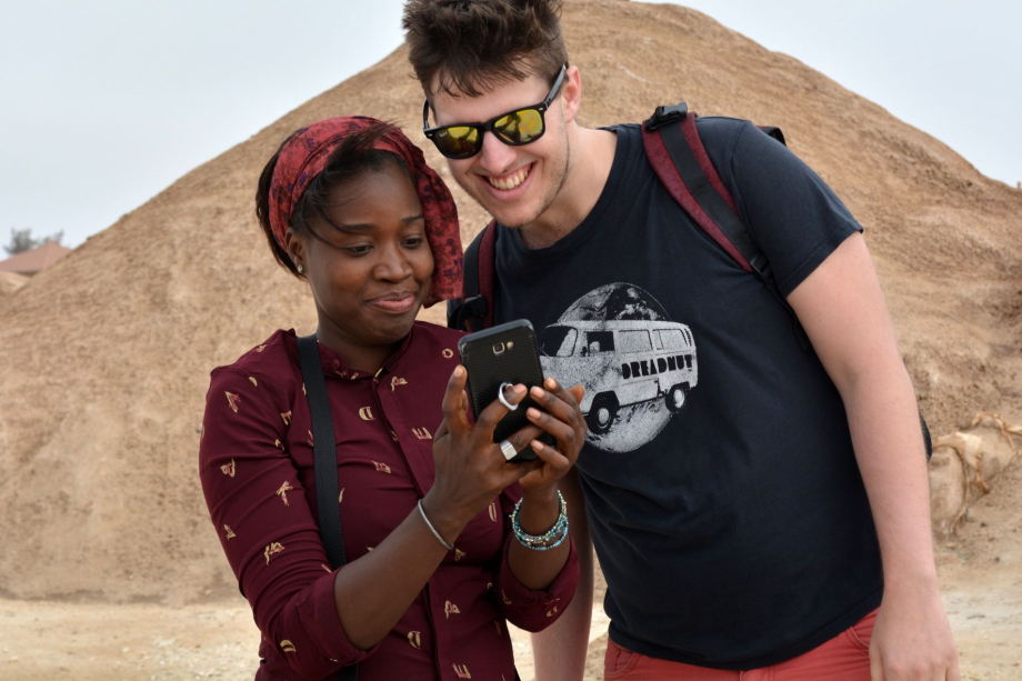 Das Bild zeigt ein Mädchen of Color und einen Jungen, die gemeinsam auf ein Smartphone blicken. 