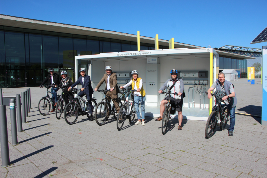 Das Bild zeigt die Geschäftsführung und Mitarbeitende der Messe Stuttgart mit E-Bikes vor der neuen Chargercube-Ladestation.