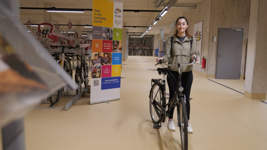 Das Bild zeigt eine Studierende mit ihrem Fahrrad in der neuen Fahrradstation an der Universität zu Köln.