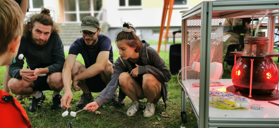 Menschen rösten Marshmallows mit Mikrobi, einer Biogas-Demonstrationsanlage