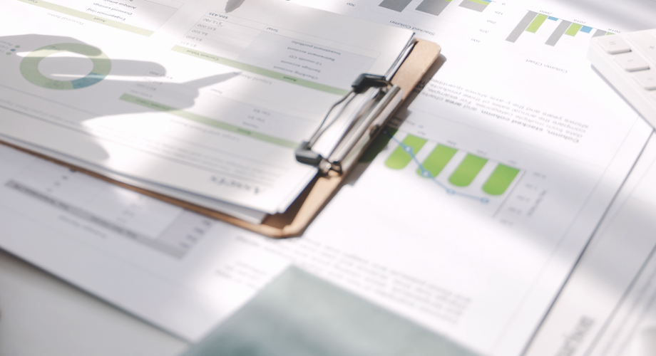 Diagramme und Tabellen mit grünen Balken auf einem Schreibtisch, Licht und Schatten über den NKI-Auswertungen.