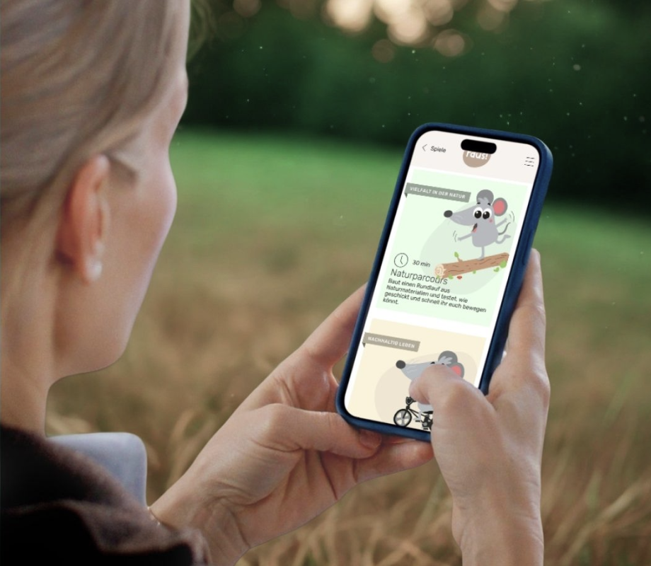 Eine Person hält im Freien ein Smartphone mit der geöffneten raus!-Spielesammlung in der Hand.