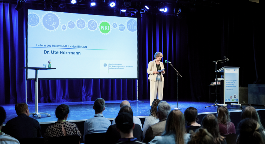 Frau Dr. Hörrmann steht auf einer Bühne vor Publikum und spricht beim Vernetzungstreffen innovativer und transformativer Klimaschutzprojekte.
