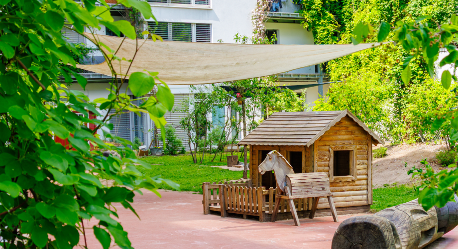 Begrünter Innenhof mit Pergola und Holzhütte.