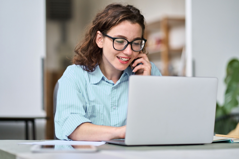Frau mit Brille sitzt vor einem Laptop.