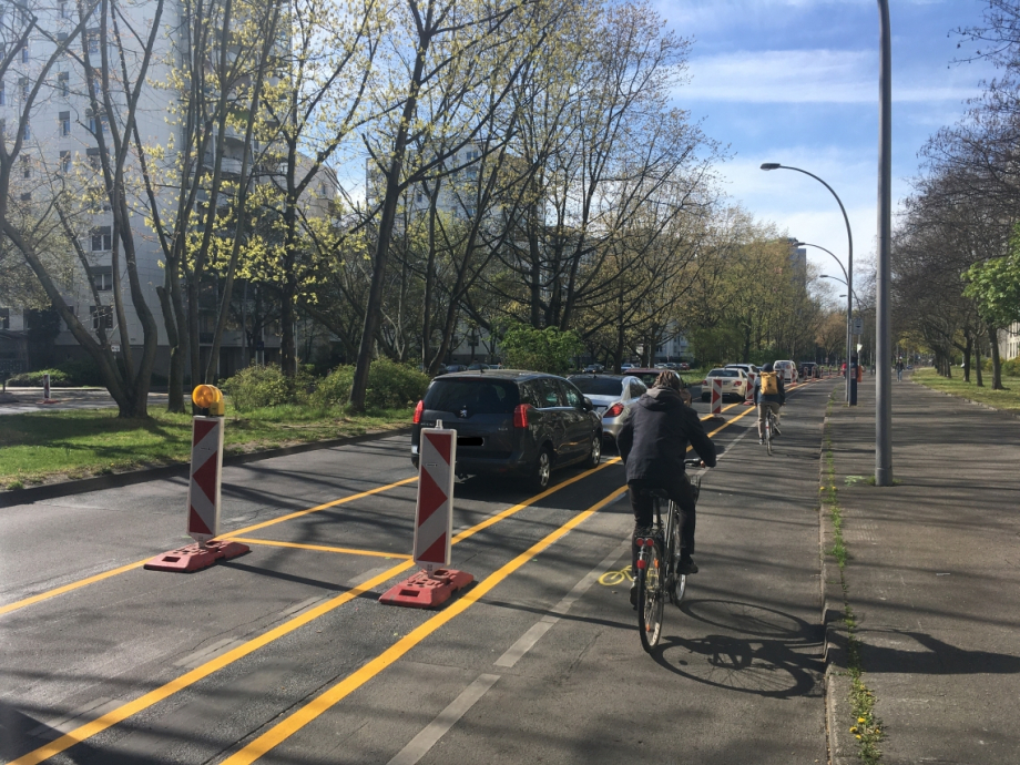 Ein gelb eingezeichneter Radweg auf einer Straße. Auf dem Weg fährt ein Radfahrer.