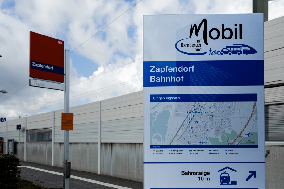 Ein Schild mit der Aufschrift Mobilstation Landkreis Bamberg steht vor einer Bahnstation