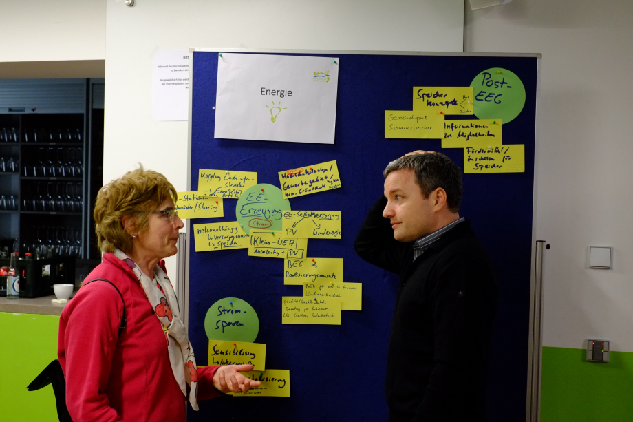 Ein Mann und eine Frau und eine Frau unterhalten sich vor einem Brainstorming-Board.