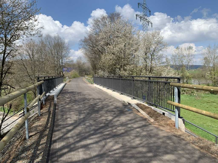 Foto von einem Radweg der über eine Brücke mit Stahl-Holz-Geländer führt