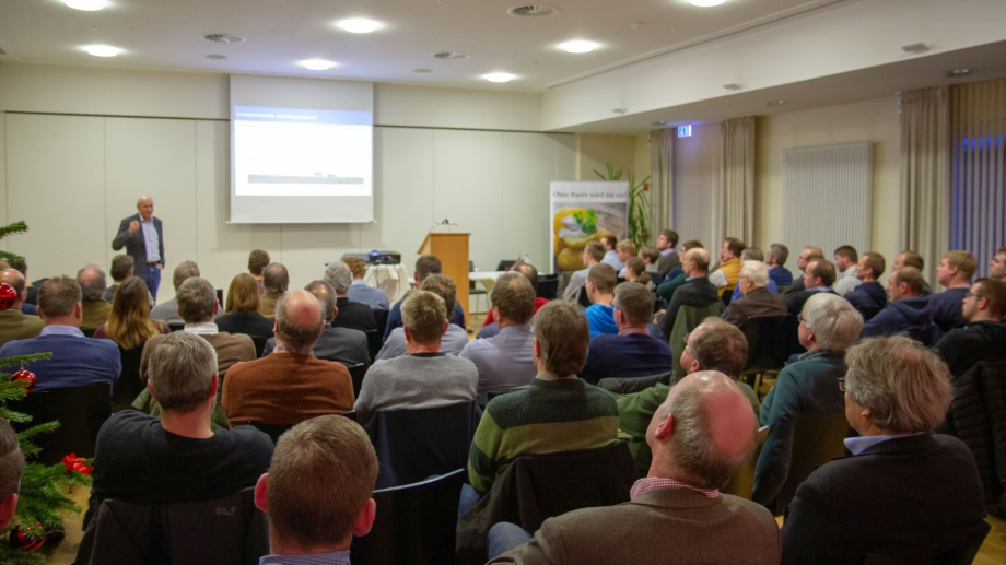 Foto von einem Raum voller sitzender Menschen, in dem ein Vortrag gehalten wird.