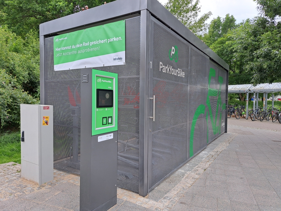 Nahaufnahme der „ParkYourBike“-Anlage mit Bedienungssäule zur Eingabe und sicheren Fahrradaufbewahrung.