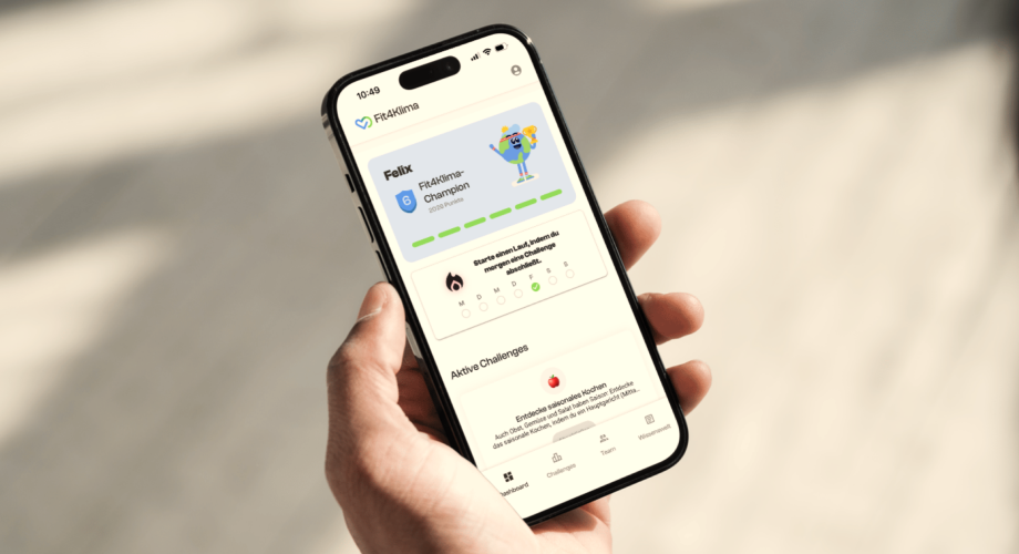 Eine Hand hält ein Smartphone mit der geöffneten Fit4Klima-App, die Punkte in einer Aufgabe und Erfolgsbalken anzeigt.