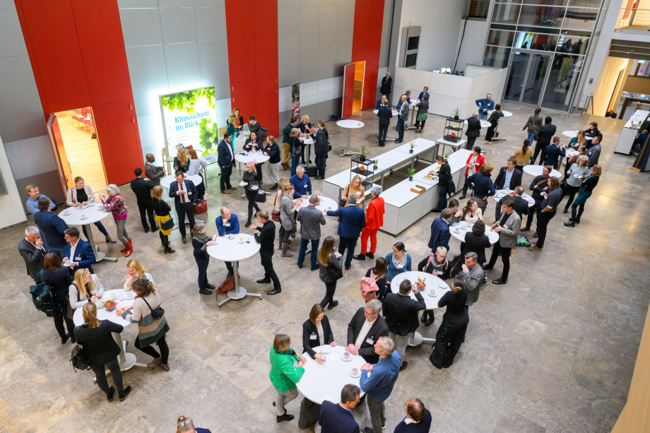 Menschen stehen in der Konferenzpause an Stehtischen 