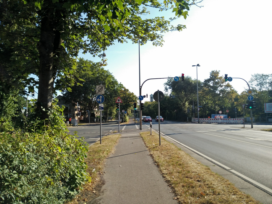 Ein Foto von einem Radweg neben einer Straßenkreuzung und einer Ampelanlage.
