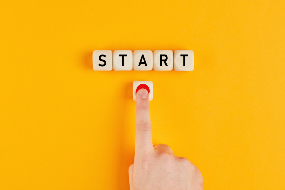 Das Foto zeigt einen Finger, der auf einen roten Punkt drückt. Darüber die Bauklötze mit dem Wort "START" vor gelbem Hintergrund.