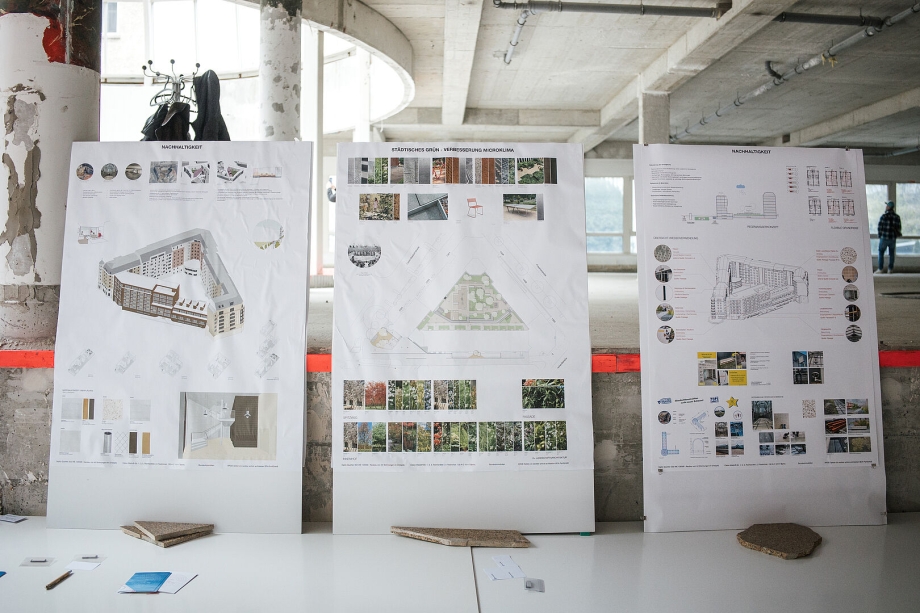 Drei große Architekturpläne stehen in einem Rohbau auf einem Tisch.