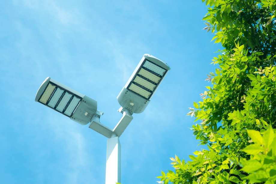 LED-Außenbeleuchtung von unten aufgenommen. Rechts wird das Bild durch die Blätter eines Baumes begrenzt.