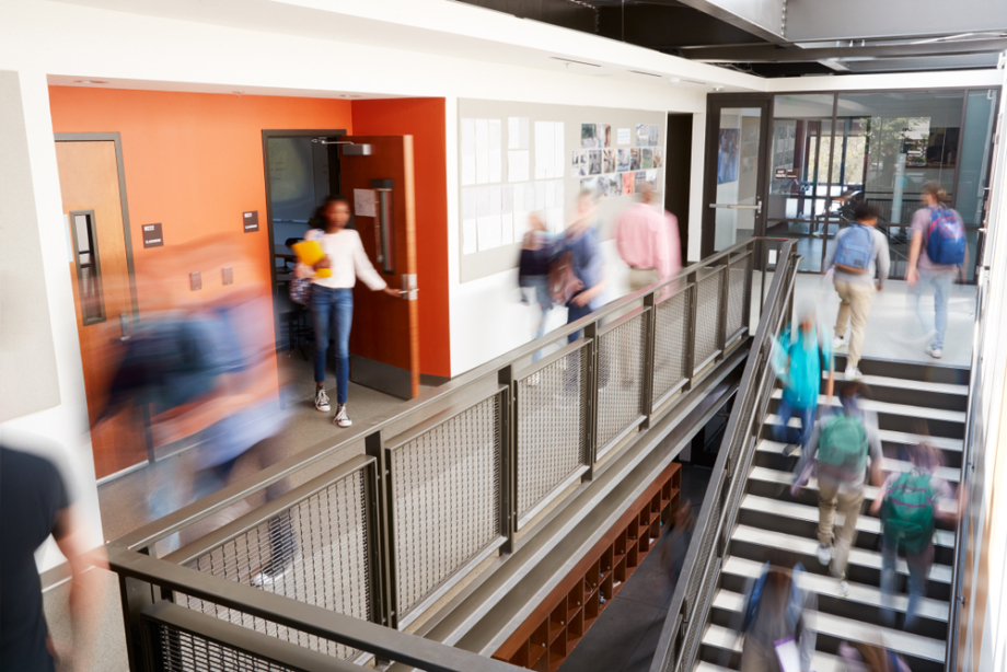 Schultreppenhaus mit Schüler*innen, die sich bewegen. 