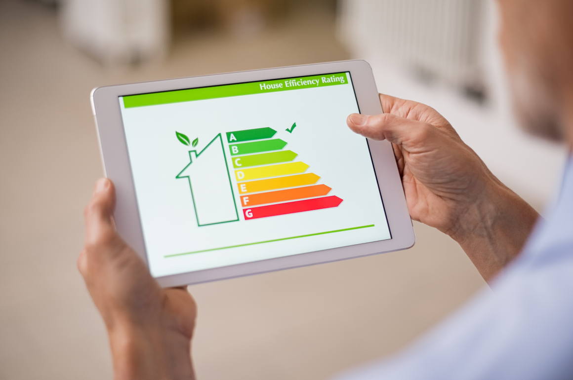 Eine Person hält ein Tablet. Auf dem Bildschirm ist die sehr gute Energieeffizienzbewertung eines Hauses zu sehen.
