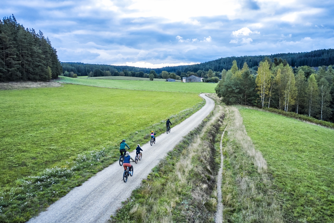 Fahrradfahrer auf einem Fahrradweg, der über eine Grüne Wiese führt.