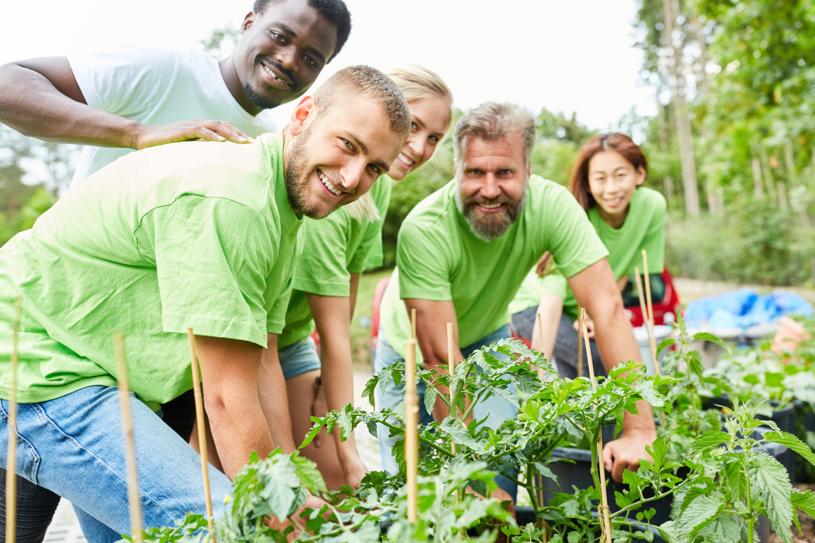 Ein Team aus Freiwilligen in grünen T-Shirts bei einer Pflanzaktion.