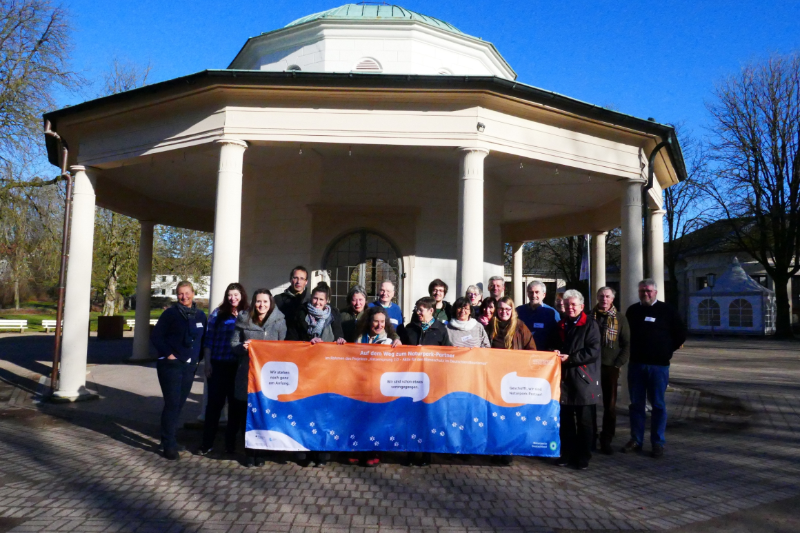 Vertreterinnen und Vertreter des Verband Deutscher Naturparke e. V. stehen vor einem Pavillon und halten ein Banner, das die „Naturpark-Partner“-Auszeichnung bewirbt.