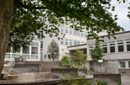 Das Bild zeigt das Kronberg Gymnasium in Aschaffenburg von außen und den Schulhof.