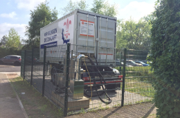 Ein LKW-Anhänger steht auf Asphalt, drumherum ein Zaun