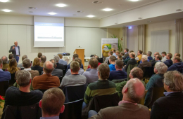 Foto von einem Raum voller sitzender Menschen, in dem ein Vortrag gehalten wird.