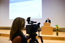 Kamerafrau mit Blick aufs Podium und einen Sprecher beim Wettbewerb Klimaaktive Kommune 2015