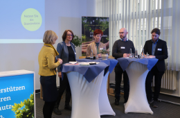 Das Foto zeigt das Podium der Veranstaltung "Bausteine der kommunalen Wärmewende" mit drei Stehtischen und fünf Personen, die sich im Austausch befinden.