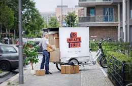 Das Bild zeDas Bild zeigt einen Mann, der Pakete in der Ladebox eines Lastenrades verstaut.igt einen Mann, der Pakete in der Ladebox eines Lastenrades verstaut.