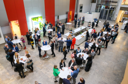 Menschen stehen in der Konferenzpause an Stehtischen 