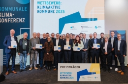 Strahlende Gesichter bei den Preisträgerinnen und Preisträgern auf der Bühne der Kommunalen Klimakonferenz in Berlin
