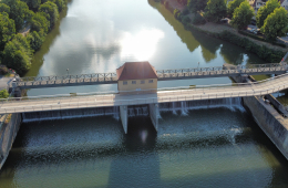 Vogelperspektive einer Brücke von oben. Links und rechts vom Fluss wachsen Bäume.