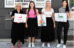 Vier Personen stehen vor einem Dienstgebäude des Landkreises Freyung-Grafenau und halten Schilder mit Abbildungen in den Händen.