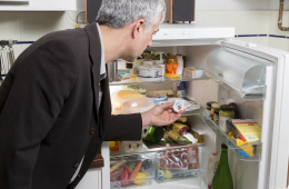 Ein Mann hängt ein Thermometer in den Kühlschrank