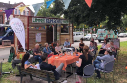 Eine Gruppe Nachbar*innen sitzt vor dem Limmer Klimaschutzmobil