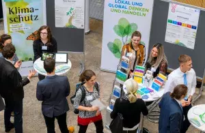 Menschen an Stehtischen vor Plakaten und Aufstellern