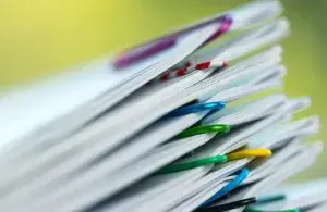 Das Foto zeigt einen Stapel mit Dokumenten, die durch bunte Büroklammern zusammengehalten werden. 