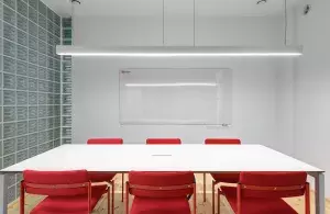Das Bild zeigt einen Raum mit Tisch und Stühlen und eine von der Decke hängende LED-Leuchte.