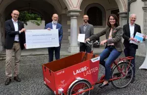 Das Bild zeigt Oberbürgermeister Uli Burchard, Stadtwerke-Geschäftsführer Dr. Norbert Reuter, Radverkehr-Beauftragter Gregor Gaffga, die Parlamentarische Staatssekretärin Schwarzelühr-Sutter auf einem Lastenfahrrad und Bürgermeister Karl Langesteiner-Schö