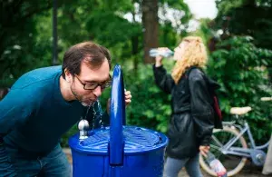 Das Bild zeigt einen Mann, der an einem Trinkbrunnen nutzt.