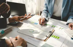 Personen besprechen gemeinsam Unterlagen mit Diagrammen und Statistiken bei der Entwicklung neuer Klimaschutzideen.