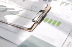 Diagramme und Tabellen mit grünen Balken auf einem Schreibtisch, Licht und Schatten über den NKI-Auswertungen.