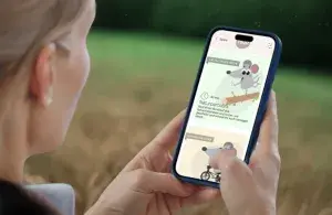 Eine Person hält im Freien ein Smartphone mit der geöffneten raus!-Spielesammlung in der Hand.