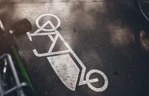 Fahrradsymbol ist auf Asphalt markiert, eingerahmt von abgestellten Fahrrädern.